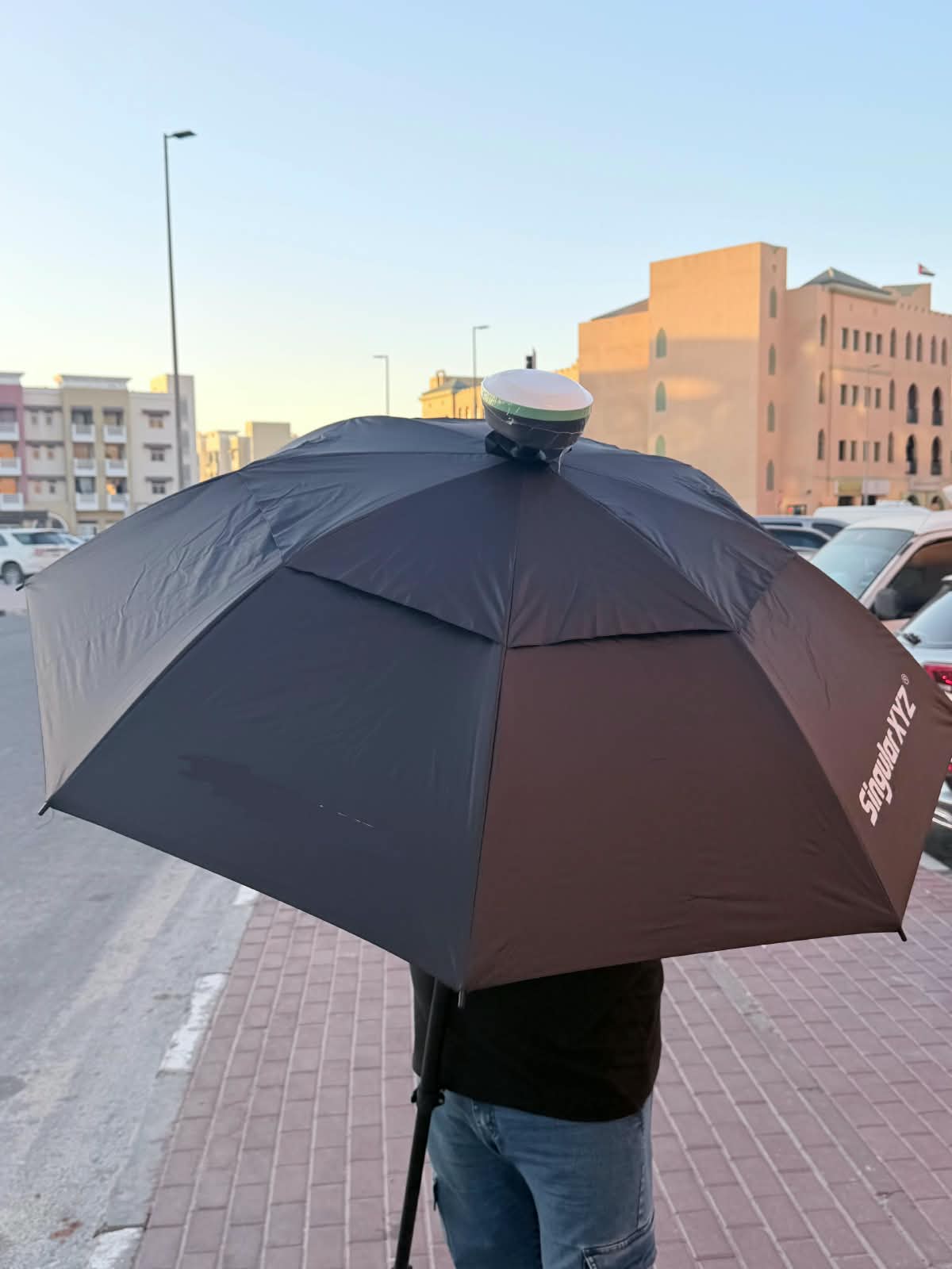 GNSS rover shaded under a survey umbrella on a Dubai street