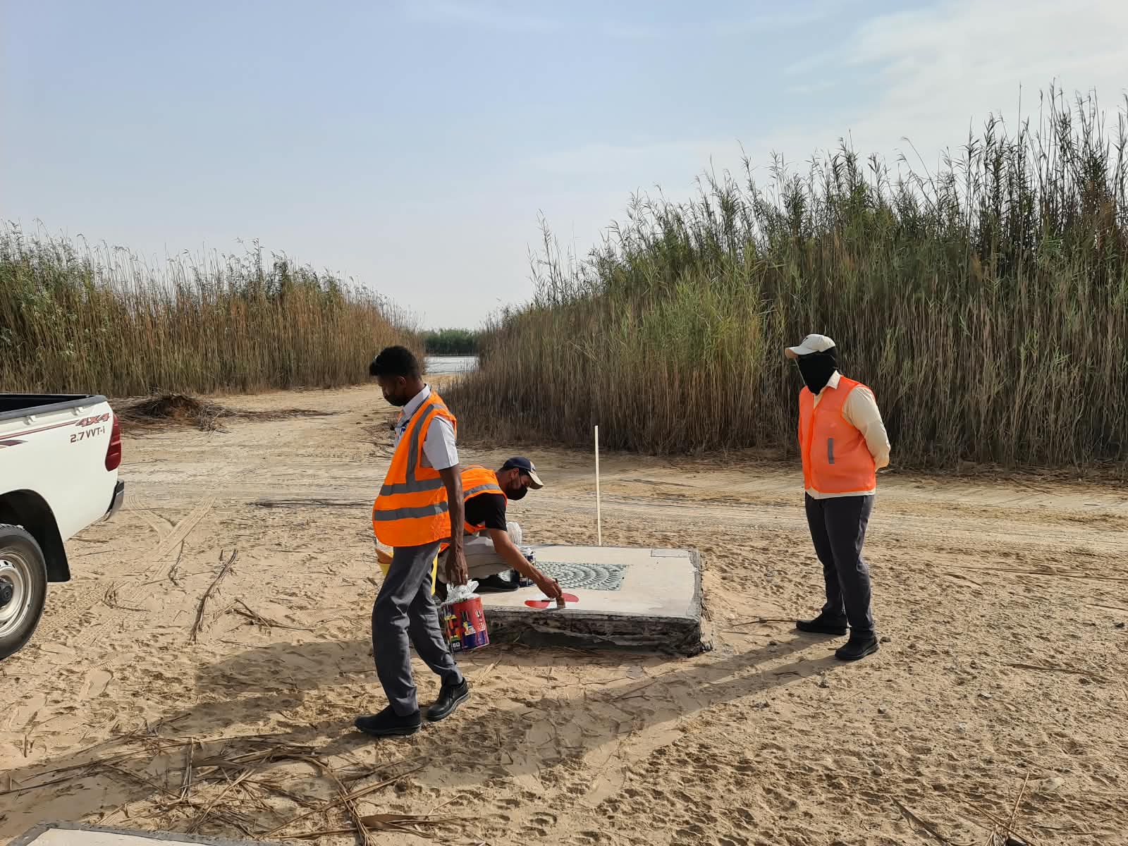 Field team marking a benchmark near a Dubai waterway